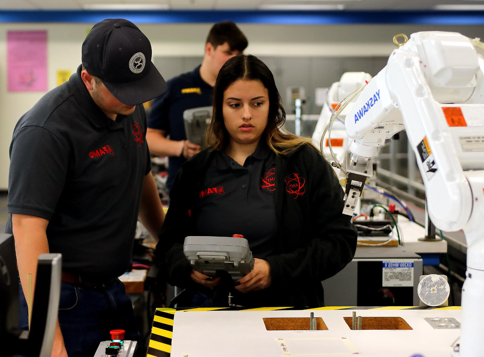 Student and instructor working with a robot arm.